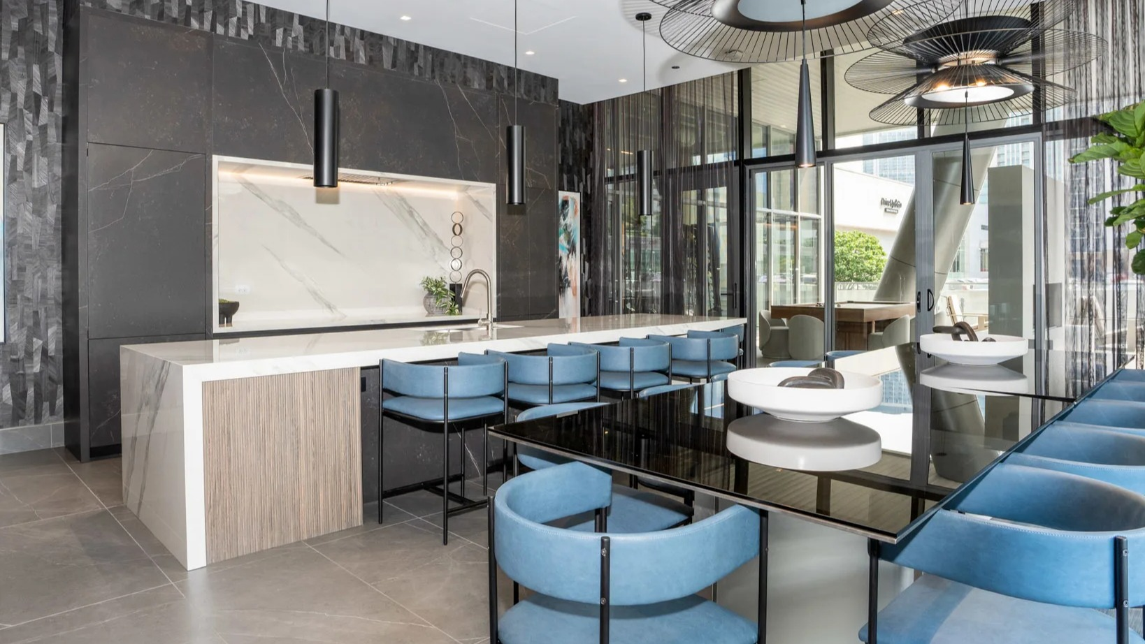 Elegant clubroom kitchen at Onni Fulton Market in Chicago, featuring a large island with seating, modern design, and unique light fixtures