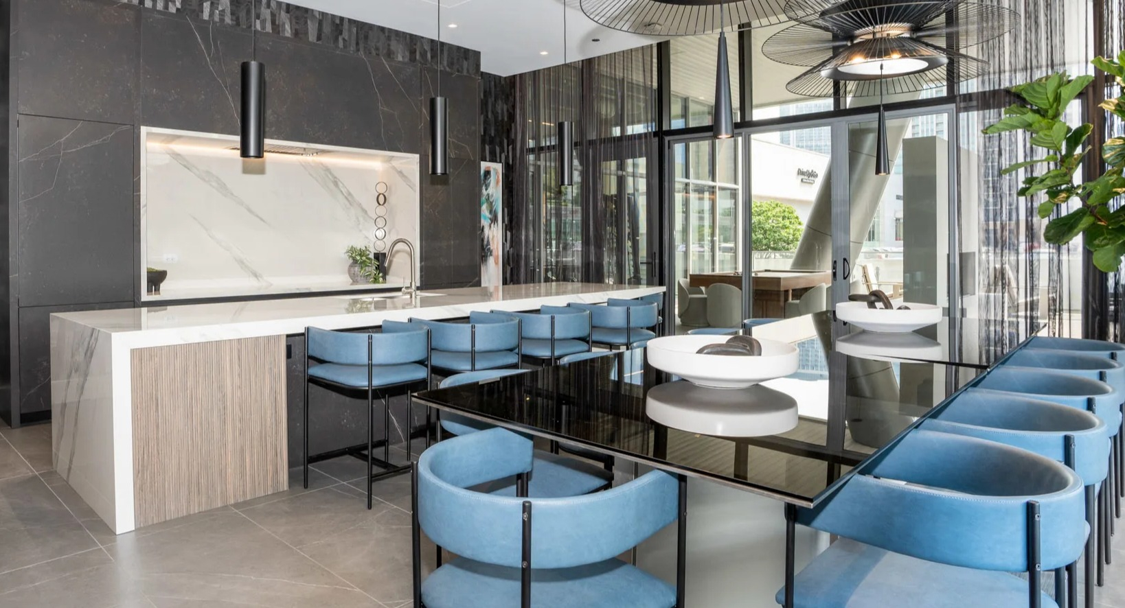 Elegant clubroom kitchen at Onni Fulton Market in Chicago, featuring a large island with seating, modern design, and unique light fixtures