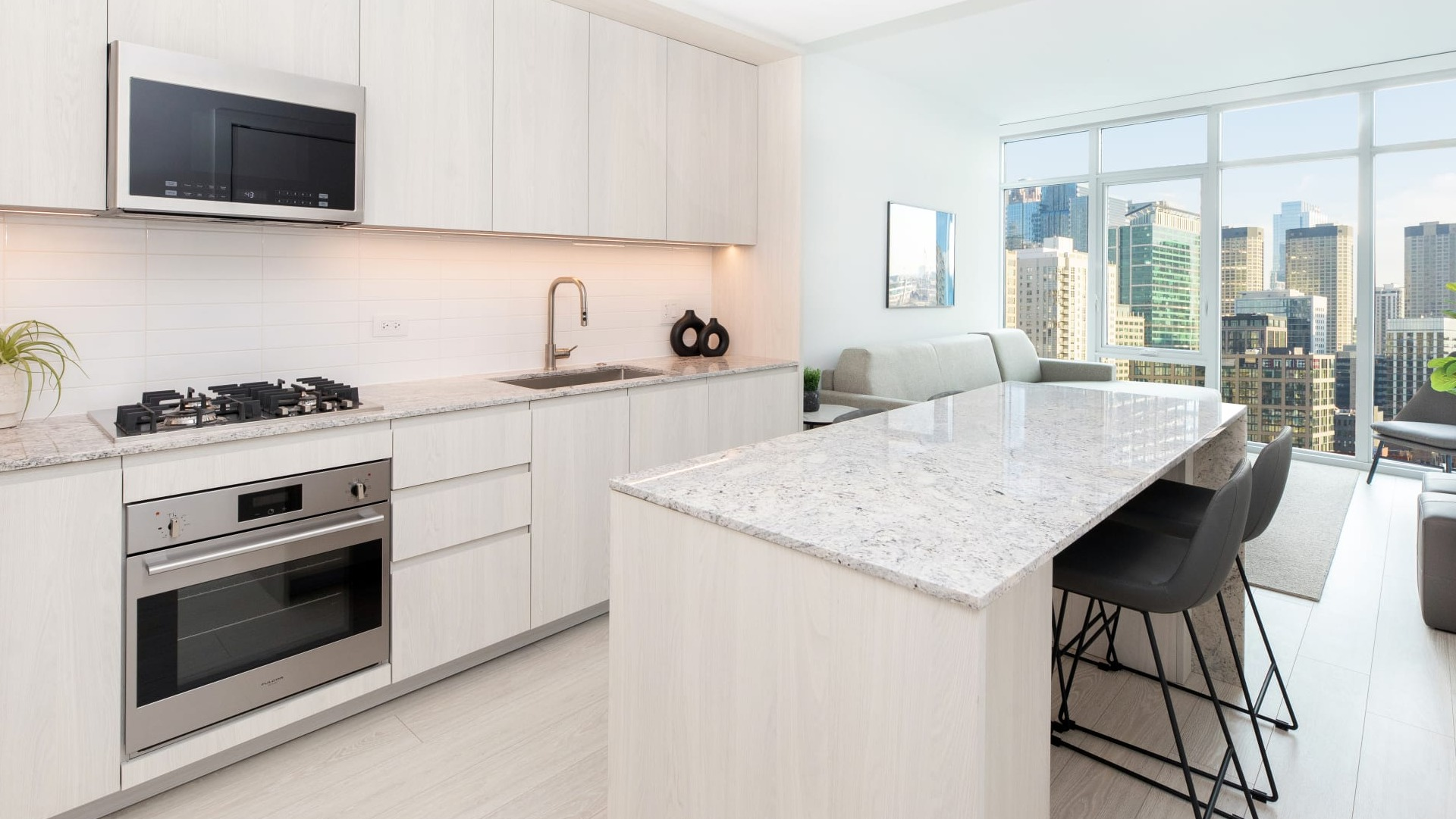 Modern open-concept kitchen and living room at Onni Fulton Market in Chicago, featuring light wood cabinets and city views
