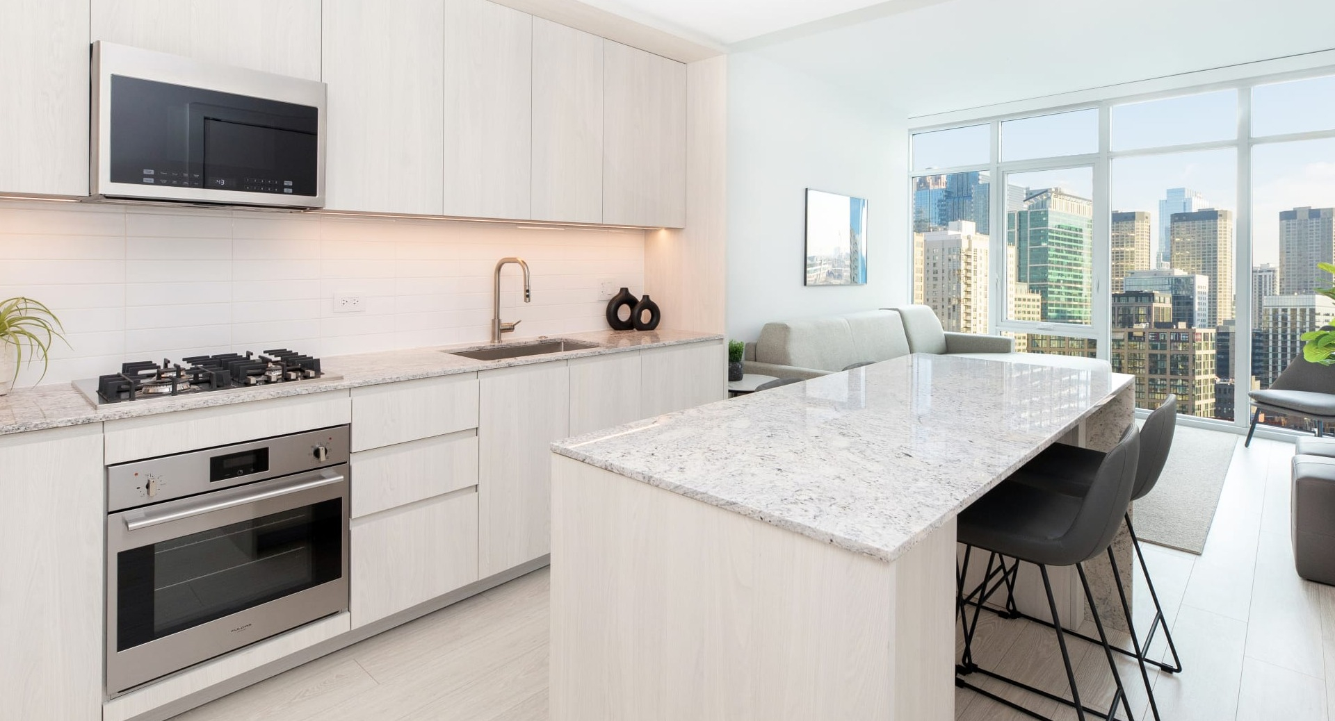 Modern open-concept kitchen and living room at Onni Fulton Market in Chicago, featuring light wood cabinets and city views
