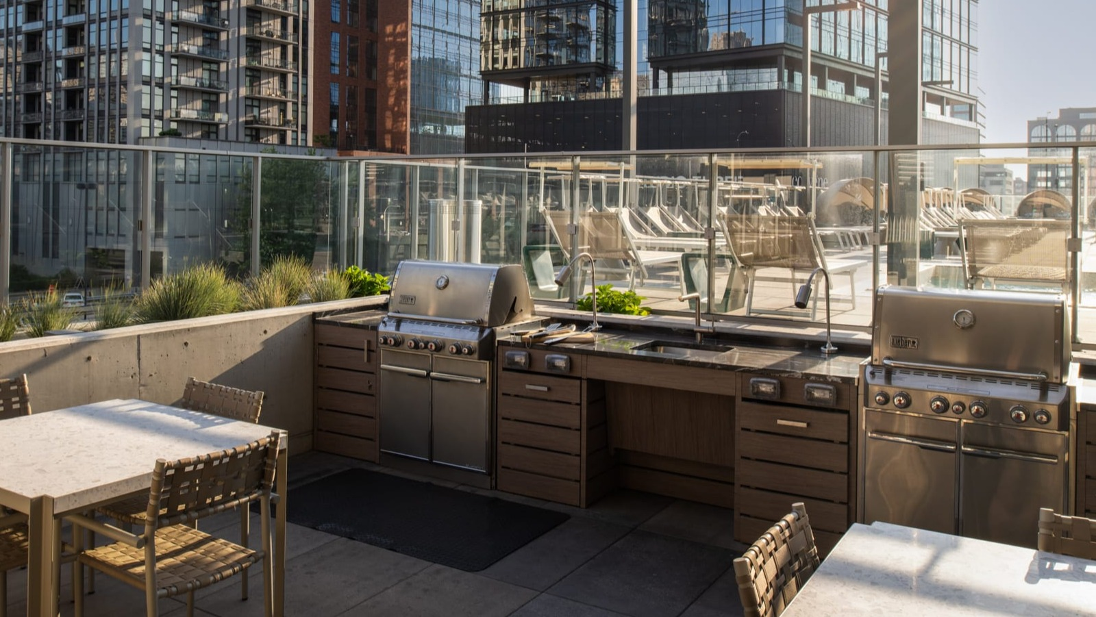 Spacious outdoor kitchen and grilling area at Onni Fulton Market in Chicago, featuring multiple grills and dining tables amidst city buildings