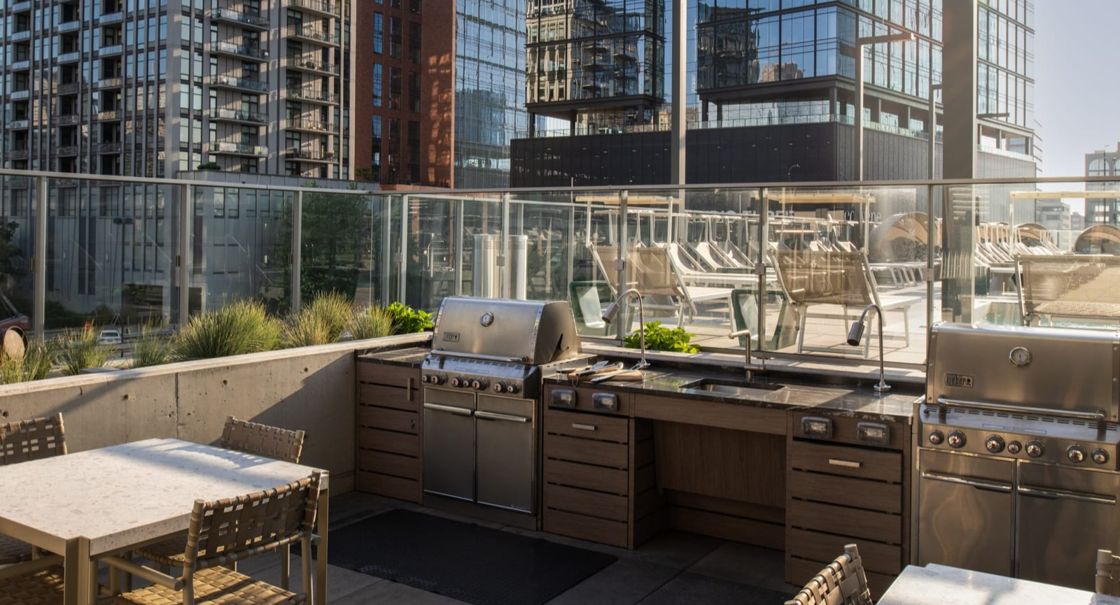 Spacious outdoor kitchen and grilling area at Onni Fulton Market in Chicago, featuring multiple grills and dining tables amidst city buildings