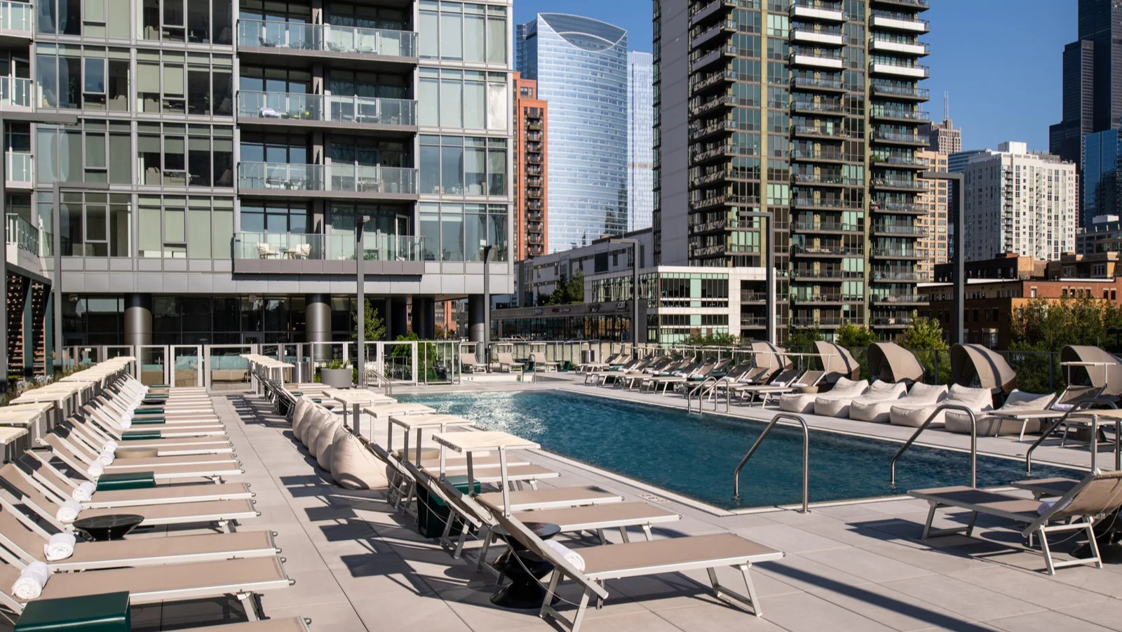 Vibrant outdoor pool deck at Onni Fulton Market in Chicago, surrounded by lounge chairs and offering striking city skyline views