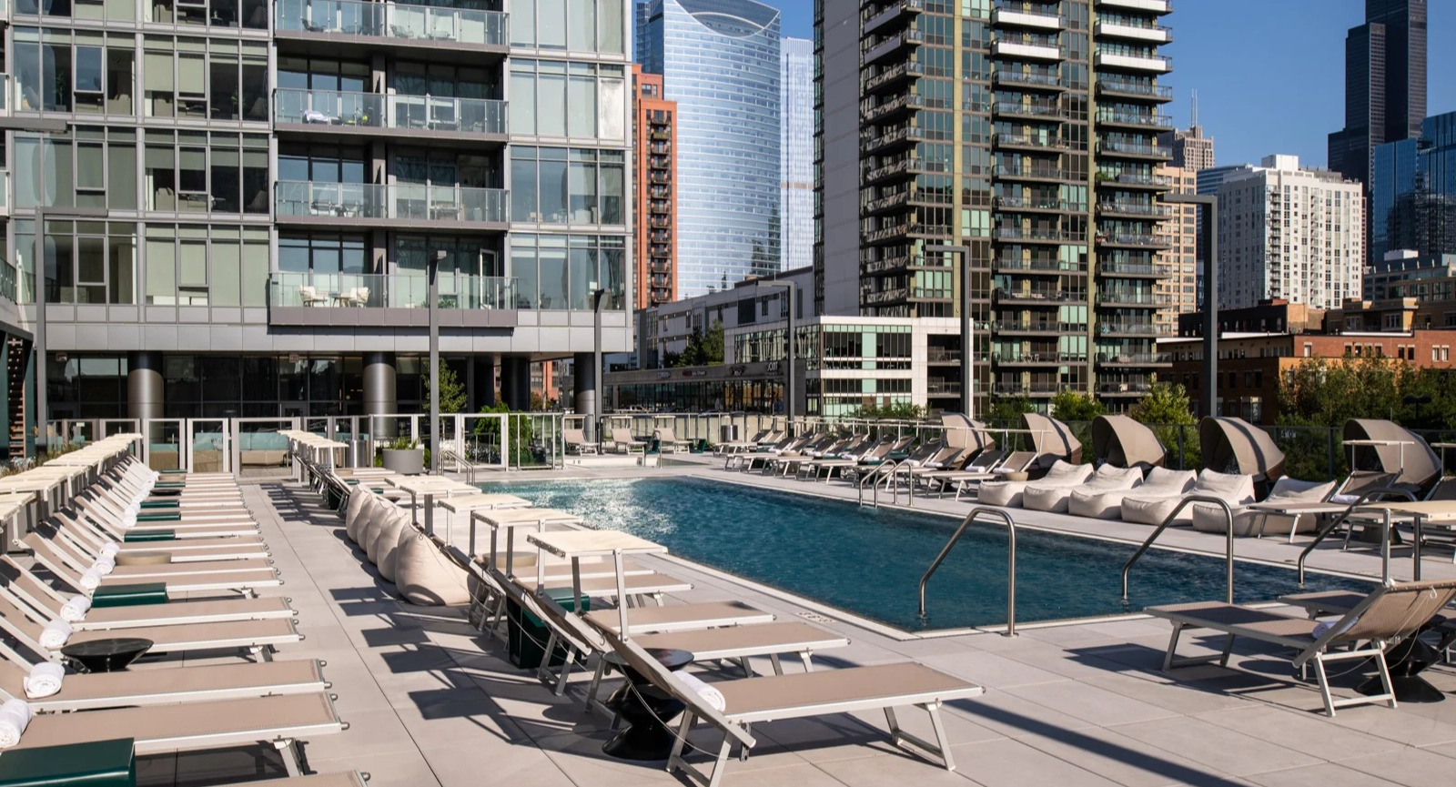 Vibrant outdoor pool deck at Onni Fulton Market in Chicago, surrounded by lounge chairs and offering striking city skyline views