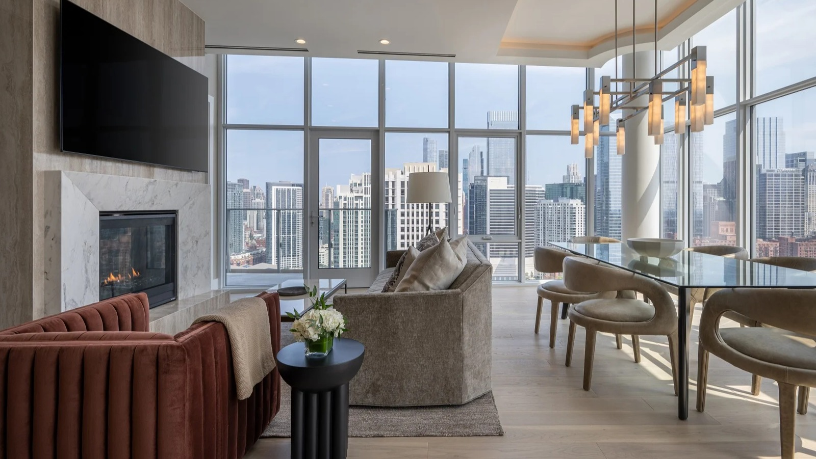 Luxurious penthouse living and dining room at Onni Fulton Market in Chicago, featuring a fireplace, elegant furniture, and expansive city views