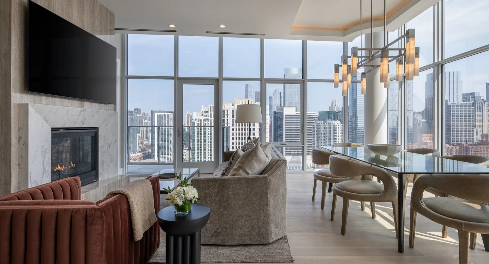 Luxurious penthouse living and dining room at Onni Fulton Market in Chicago, featuring a fireplace, elegant furniture, and expansive city views