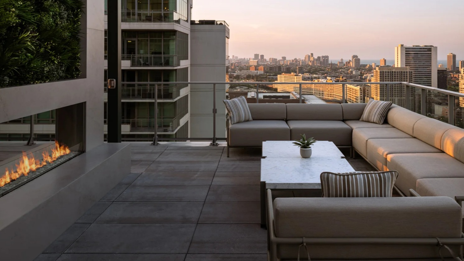 Chic rooftop lounge at Onni Fulton Market in Chicago, featuring a modern outdoor fireplace, comfortable seating, and sunset city views