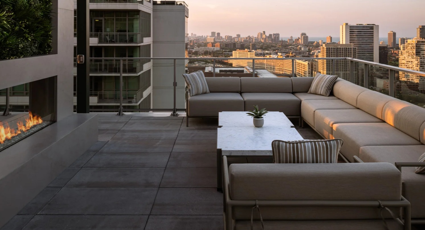 Chic rooftop lounge at Onni Fulton Market in Chicago, featuring a modern outdoor fireplace, comfortable seating, and sunset city views