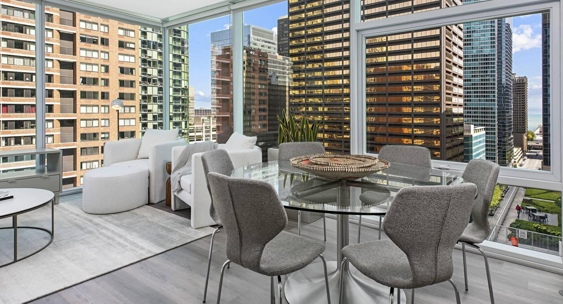Corner dining and living area at Optima Signature with glass walls, round table, and skyline views ideal for entertaining in Chicago