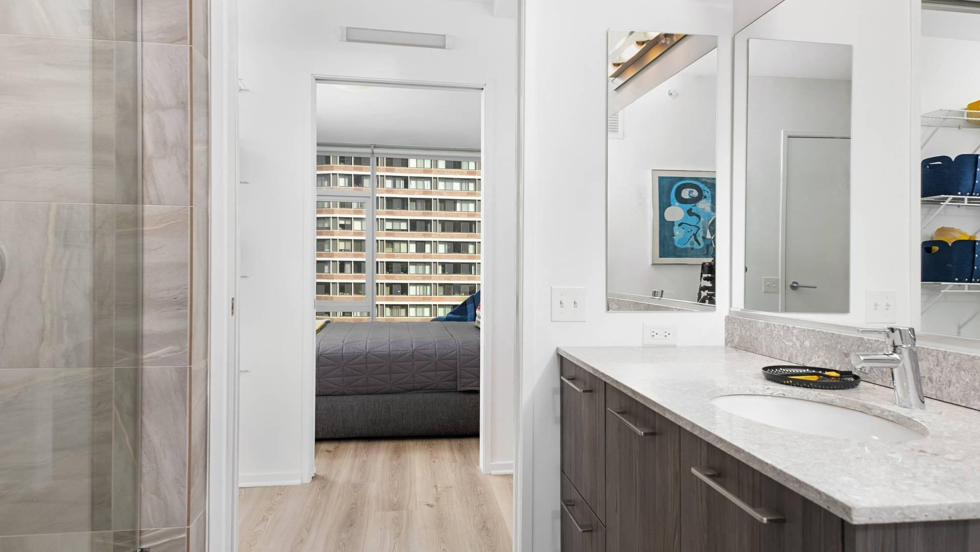 Ensuite bath at Optima Signature with stone vanity and glass shower, opening to a walk-in closet and bedroom for easy daily flow