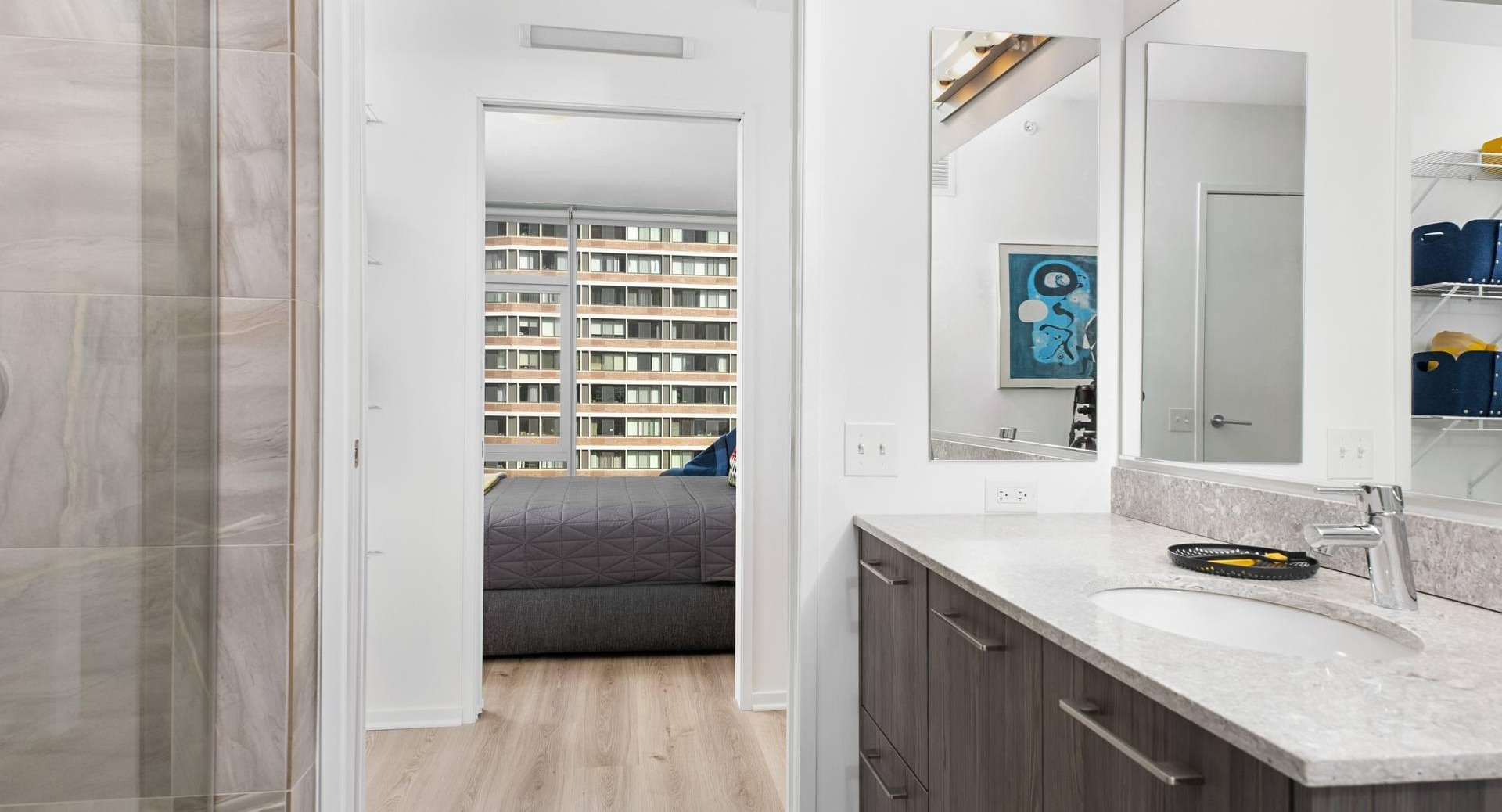 Ensuite bath at Optima Signature with stone vanity and glass shower, opening to a walk-in closet and bedroom for easy daily flow