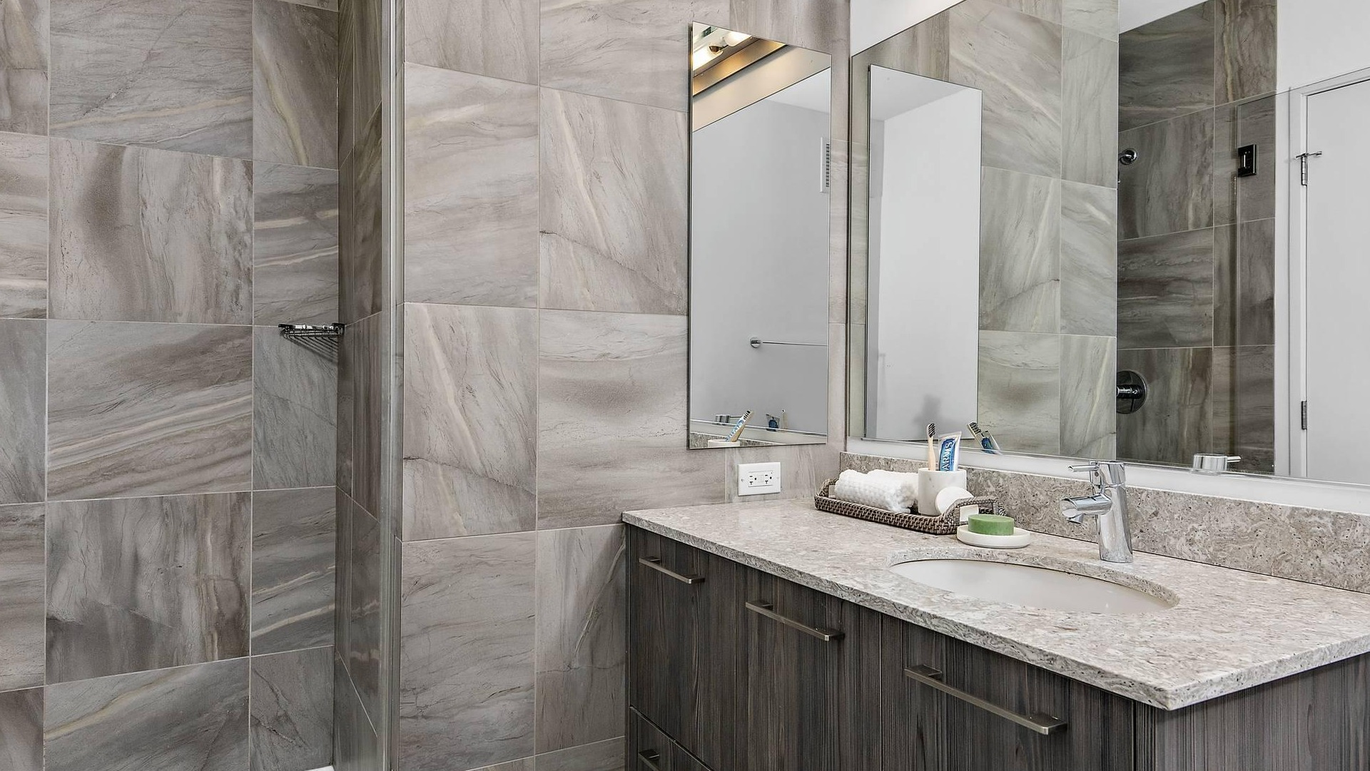 Modern bathroom at Optima Signature with glass shower, stone vanity, and sleek gray tile finishes
