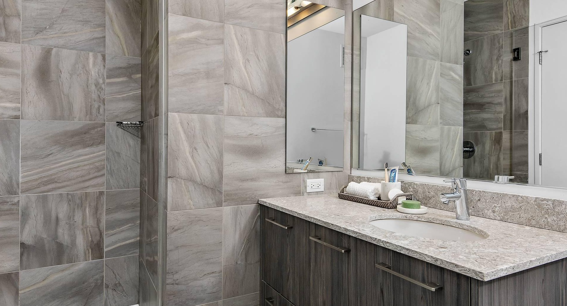 Modern bathroom at Optima Signature with glass shower, stone vanity, and sleek gray tile finishes