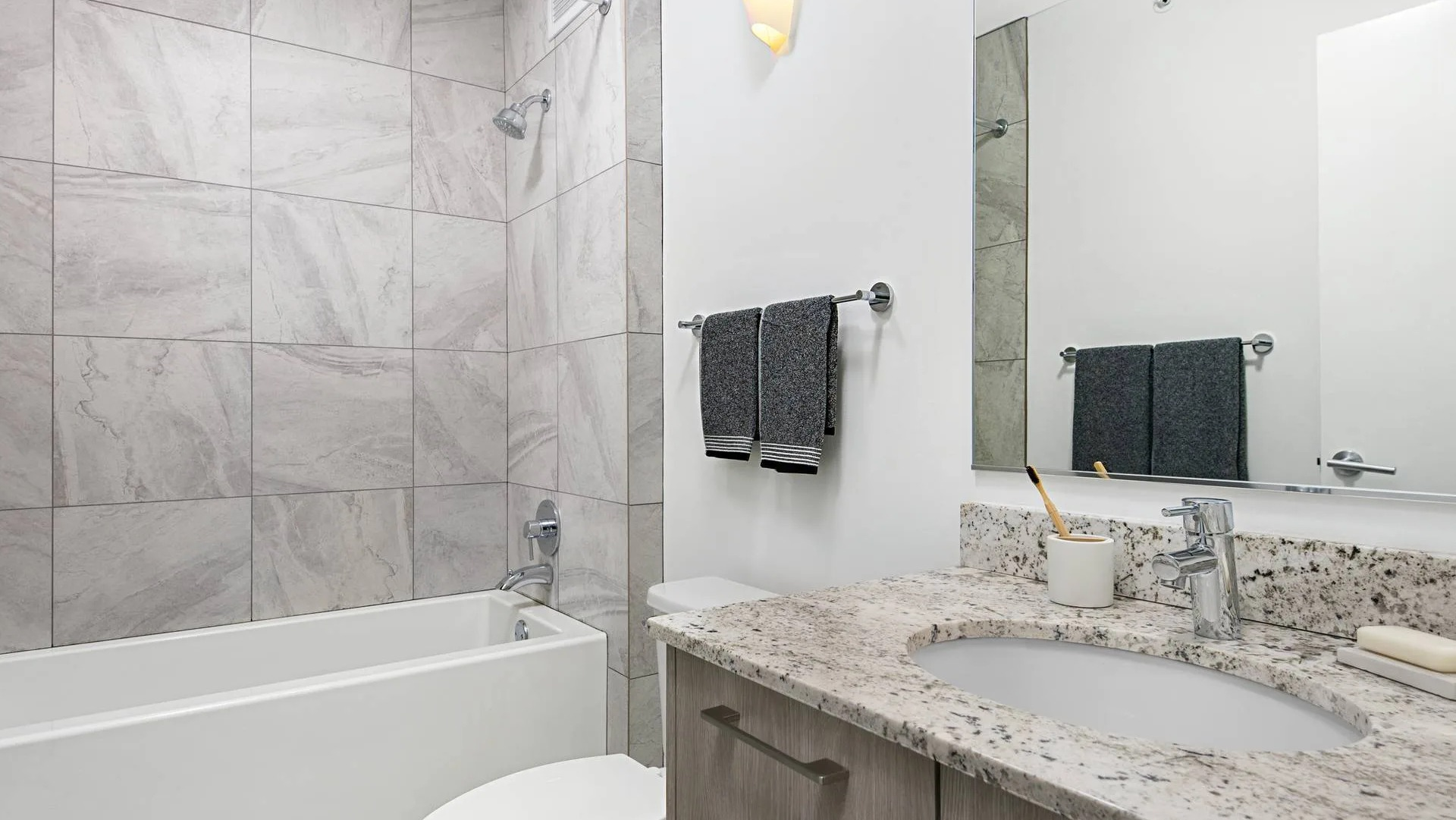 Modern bathroom at Optima Signature with large tub-shower combo, stone vanity, and neutral tile for a clean, move-in-ready feel