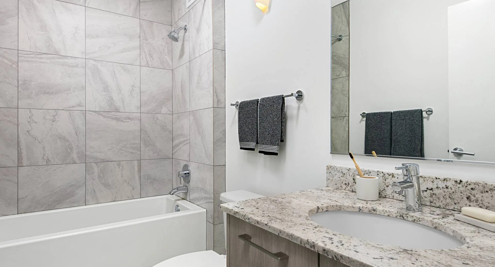 Modern bathroom at Optima Signature with large tub-shower combo, stone vanity, and neutral tile for a clean, move-in-ready feel