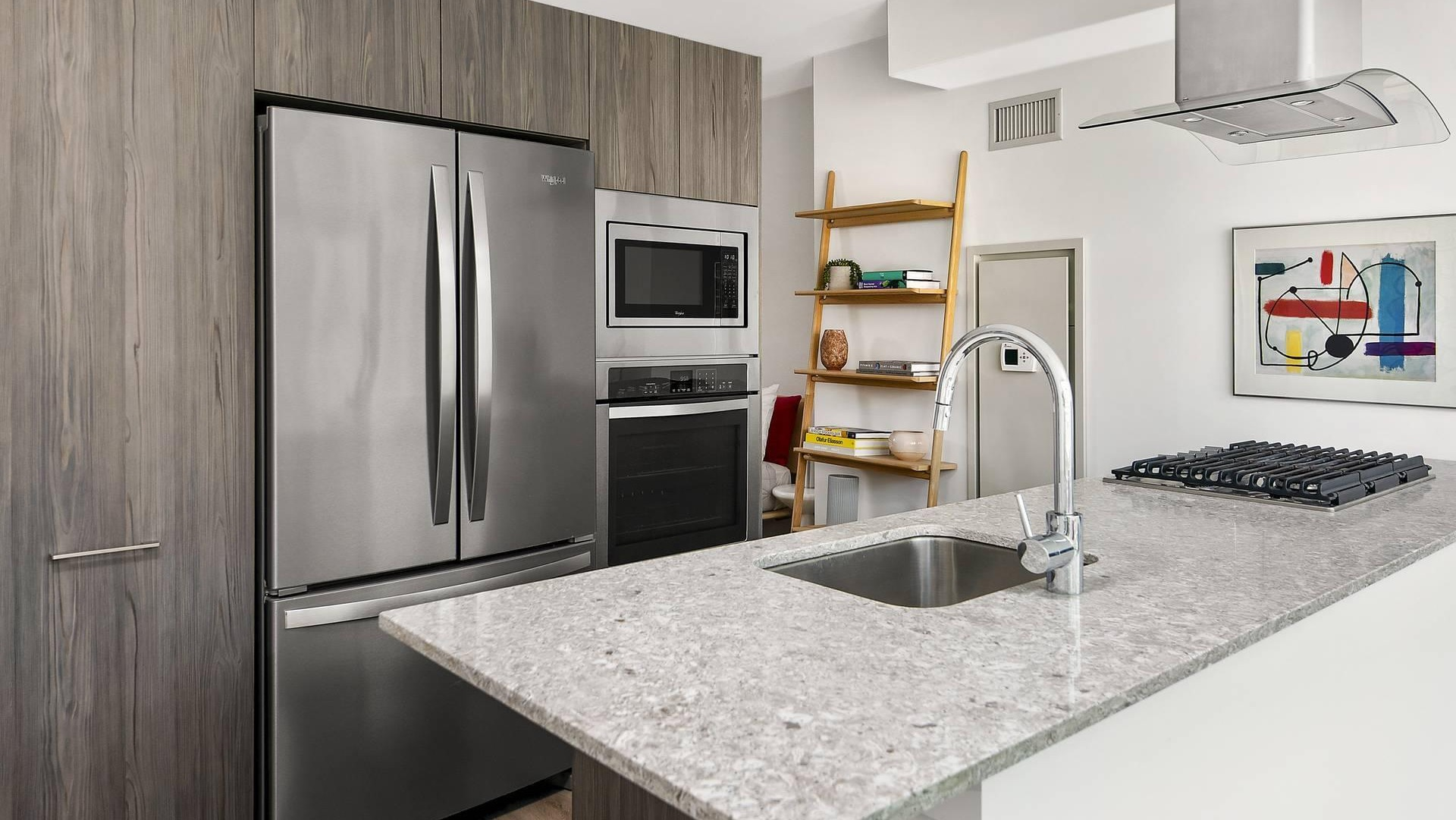 Open kitchen layout at Optima Signature with granite counters, stainless steel fridge, and wood cabinetry