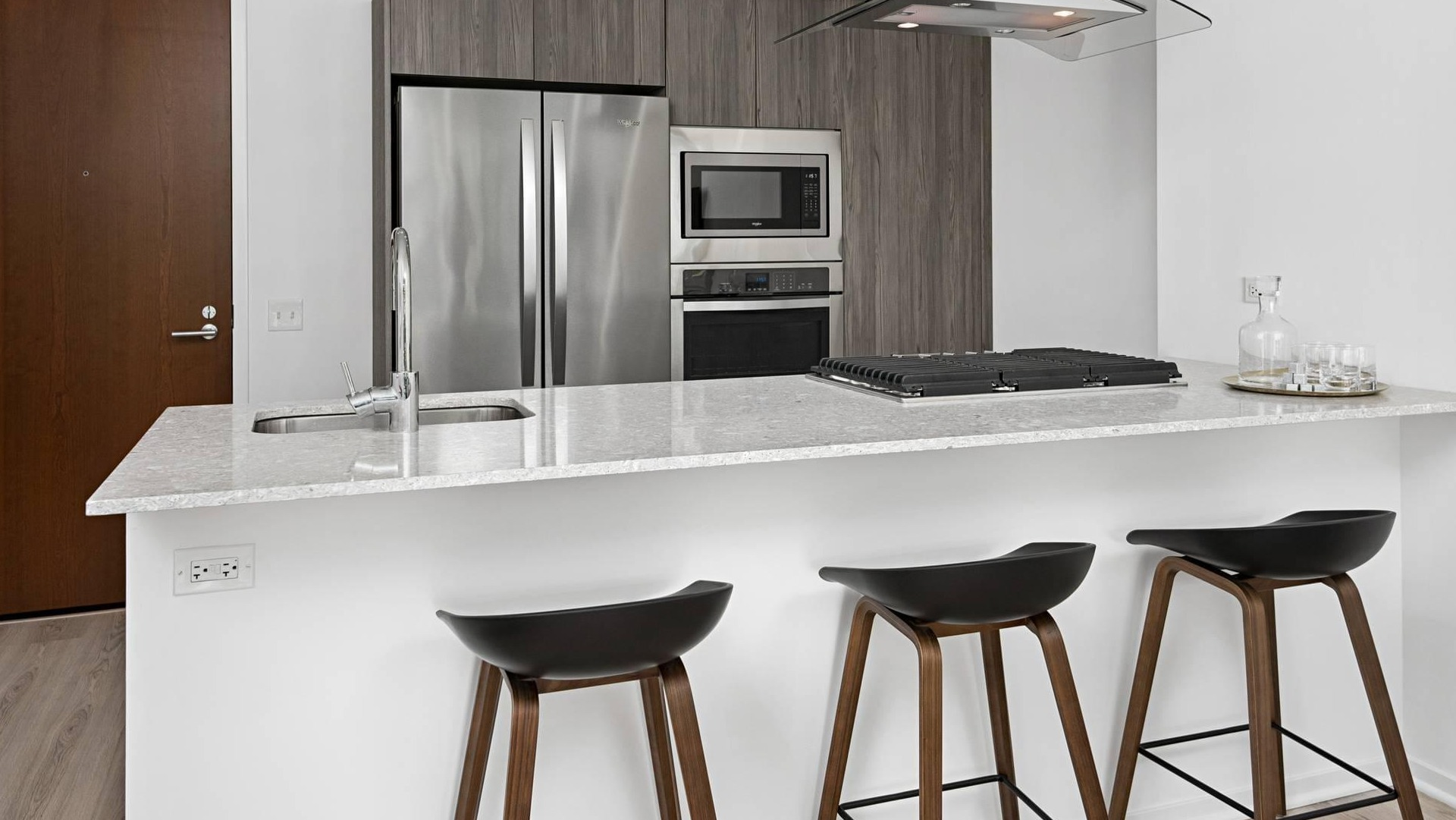 Modern kitchen at Optima Signature with sleek cabinetry, stainless steel appliances, and a breakfast bar with seating