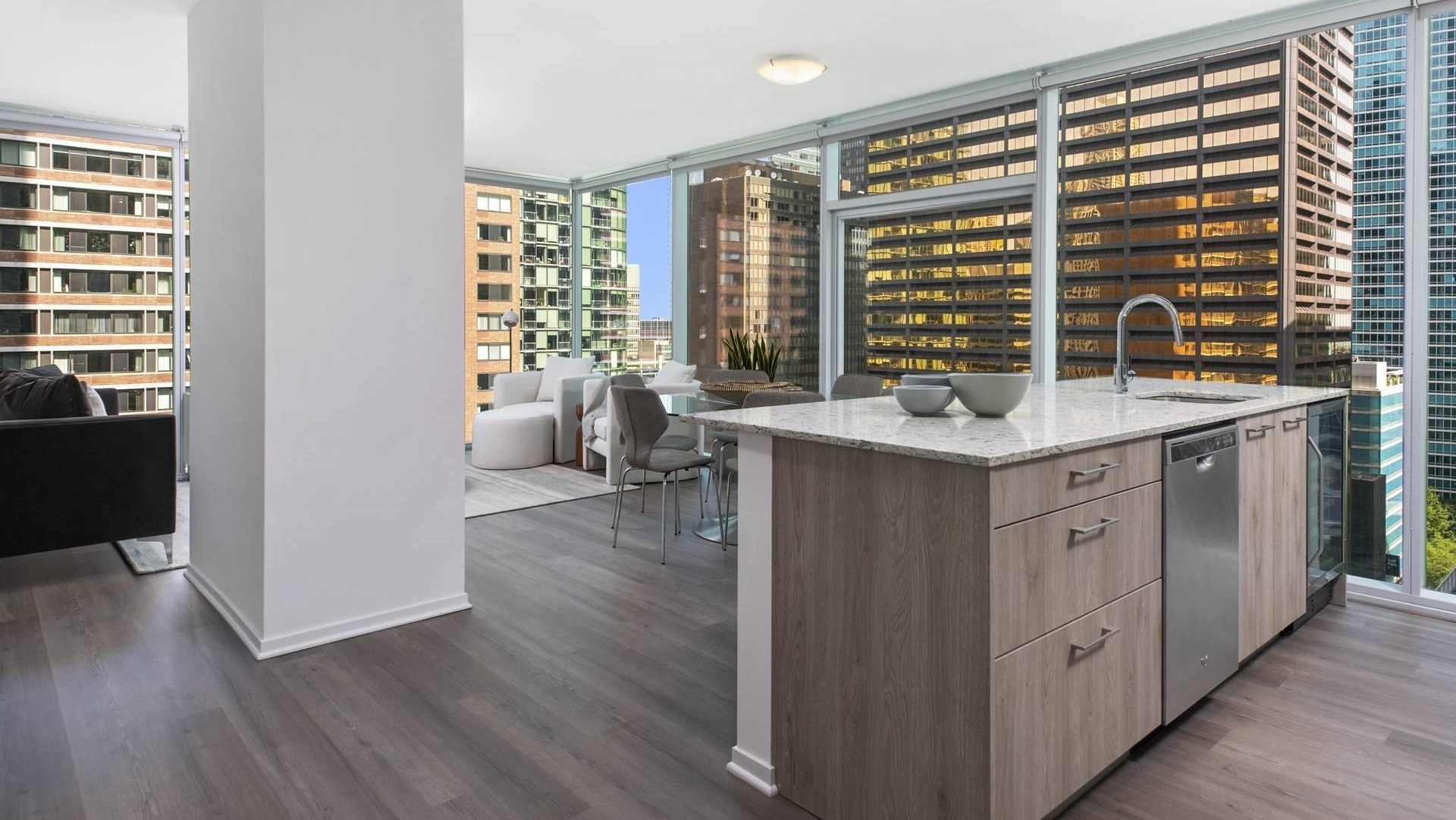 Open-concept layout at Optima Signature showing kitchen island, dining area, and living space wrapped in floor-to-ceiling windows