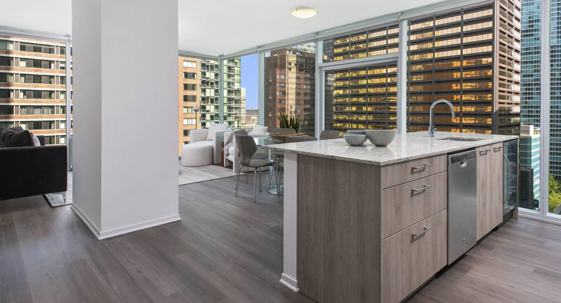 Open-concept layout at Optima Signature showing kitchen island, dining area, and living space wrapped in floor-to-ceiling windows