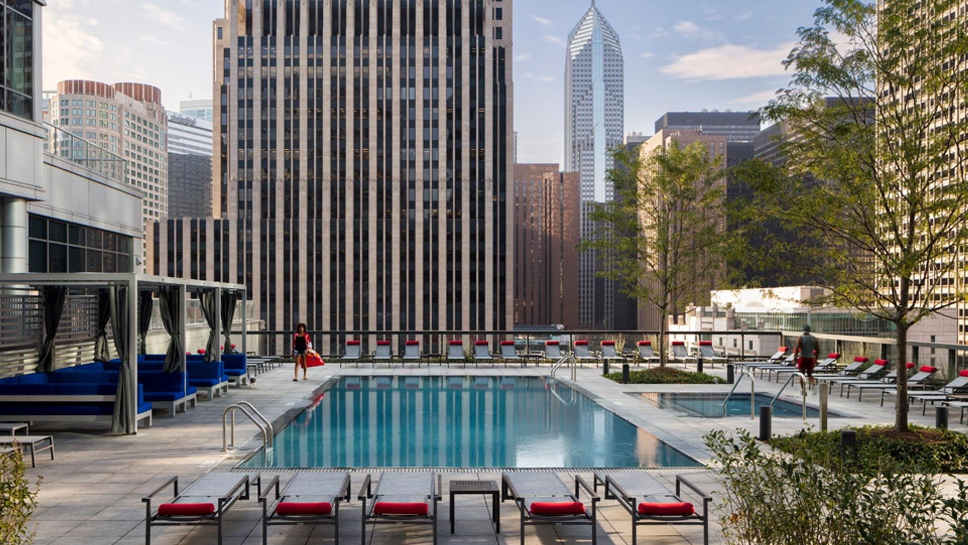 Outdoor swimming pool at Optima Signature with lounge chairs, shaded cabanas, and striking Chicago skyline views