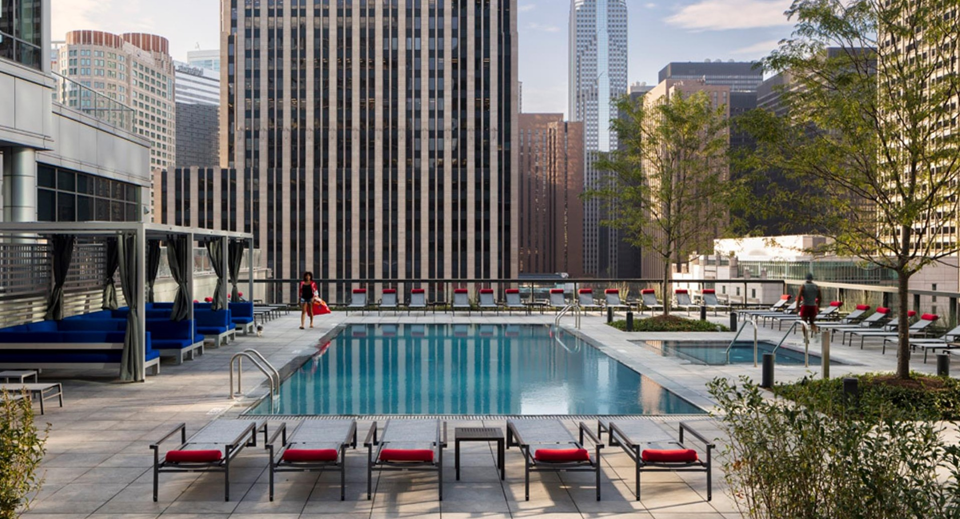 Outdoor swimming pool at Optima Signature with lounge chairs, shaded cabanas, and striking Chicago skyline views
