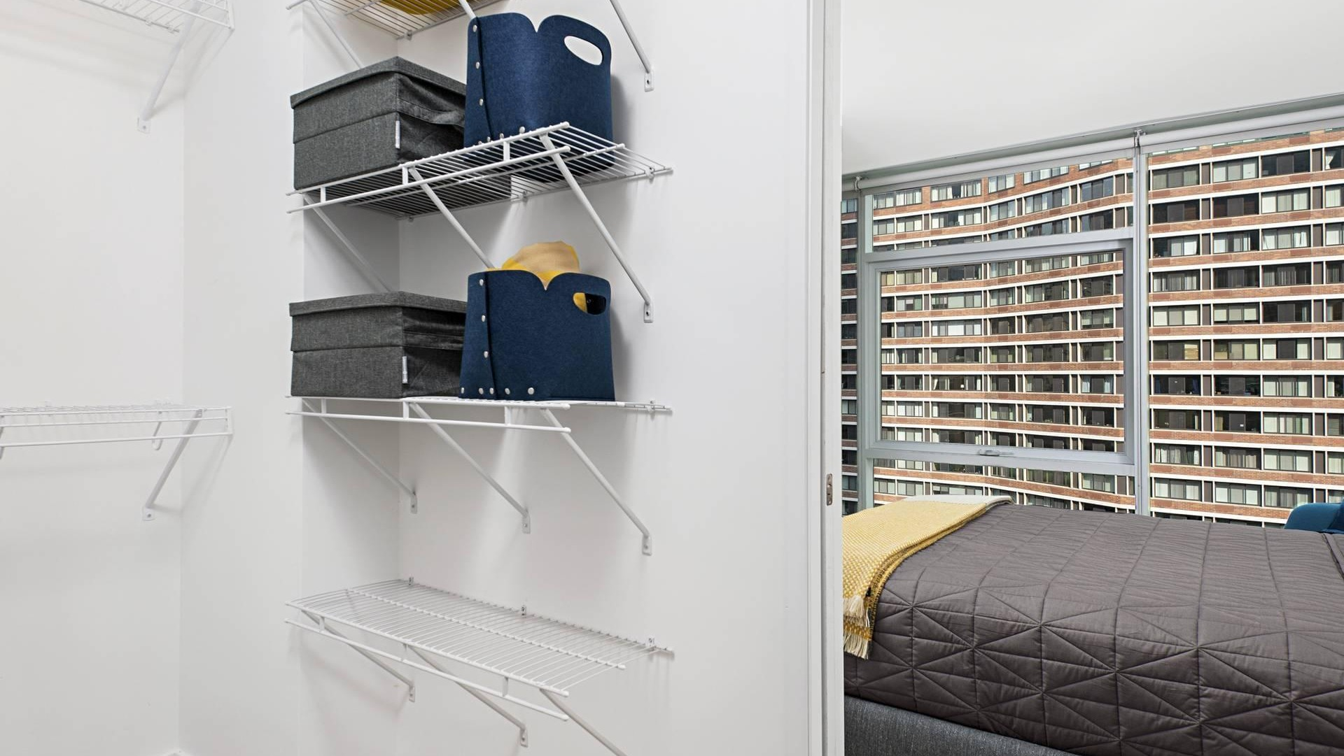 Spacious walk-in closet at Optima Signature with white wire shelving, connected to a bright bedroom with modern finishes
