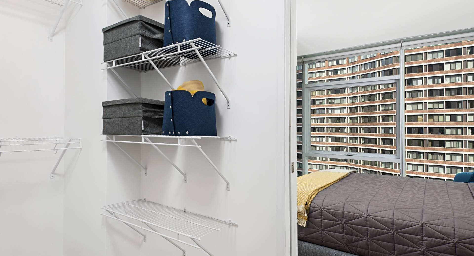 Spacious walk-in closet at Optima Signature with white wire shelving, connected to a bright bedroom with modern finishes