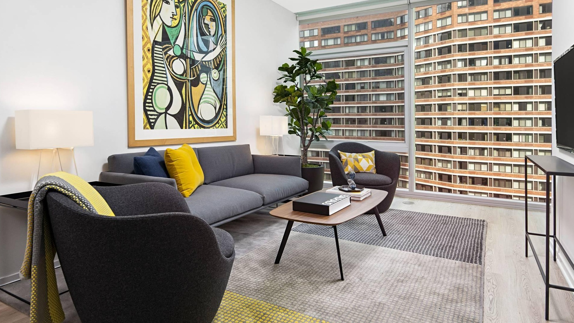 Stylish living room at Optima Signature with contemporary gray furniture, bold wall art, and full-height windows showcasing the skyline