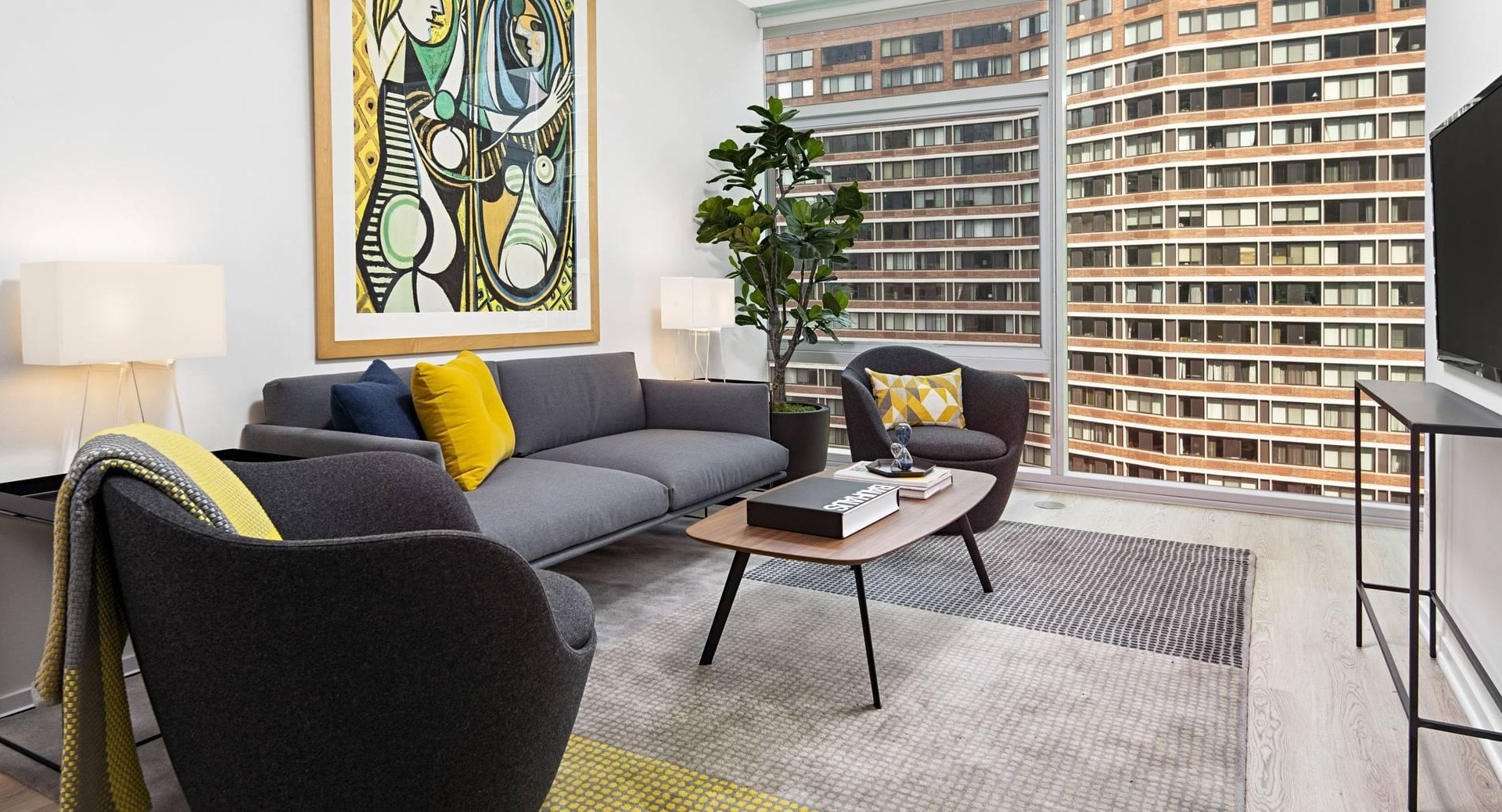 Stylish living room at Optima Signature with contemporary gray furniture, bold wall art, and full-height windows showcasing the skyline