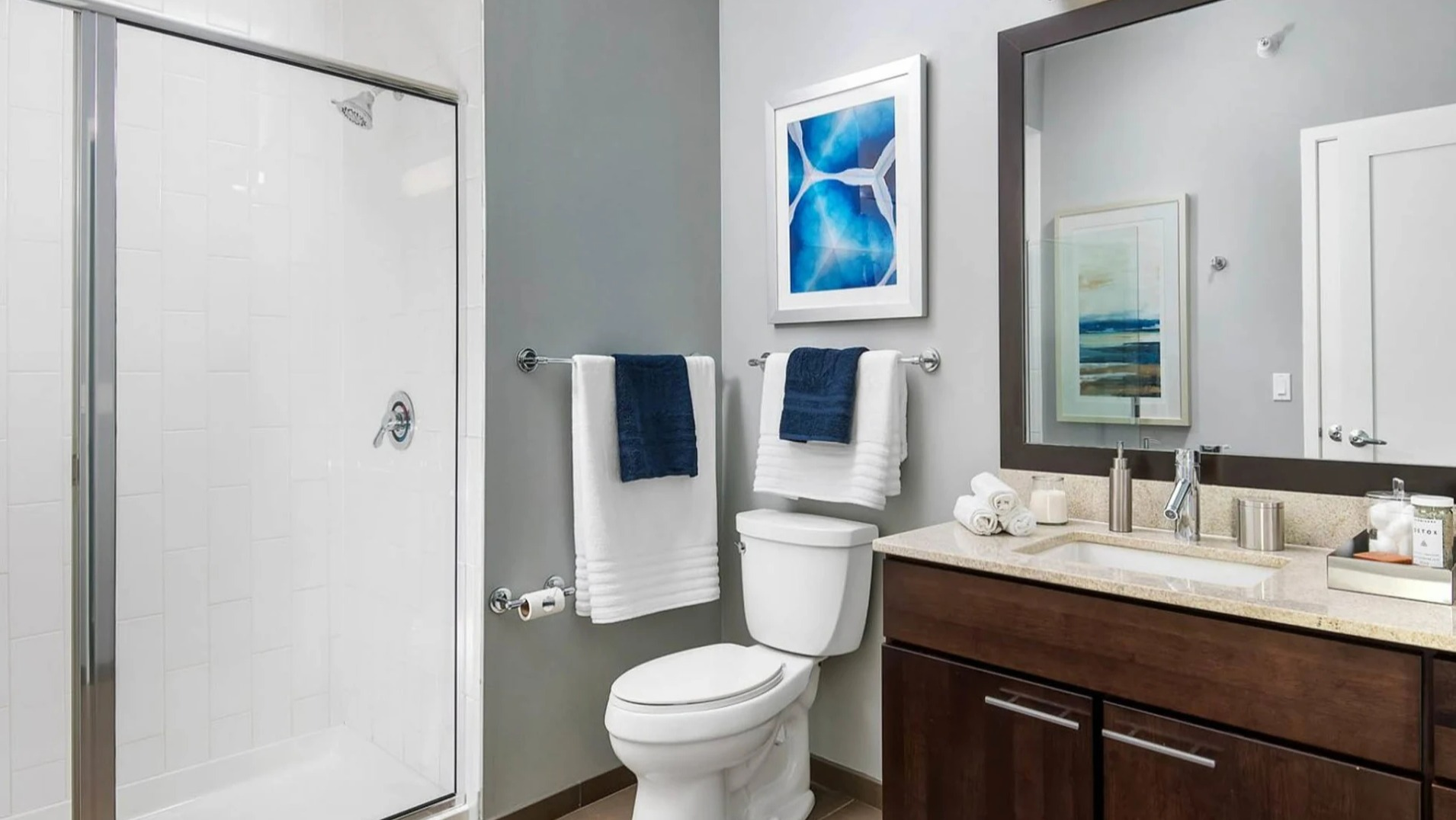 Modern apartment bathroom at Parc Huron in Chicago, featuring a walk-in shower, vanity with storage, and contemporary fixtures