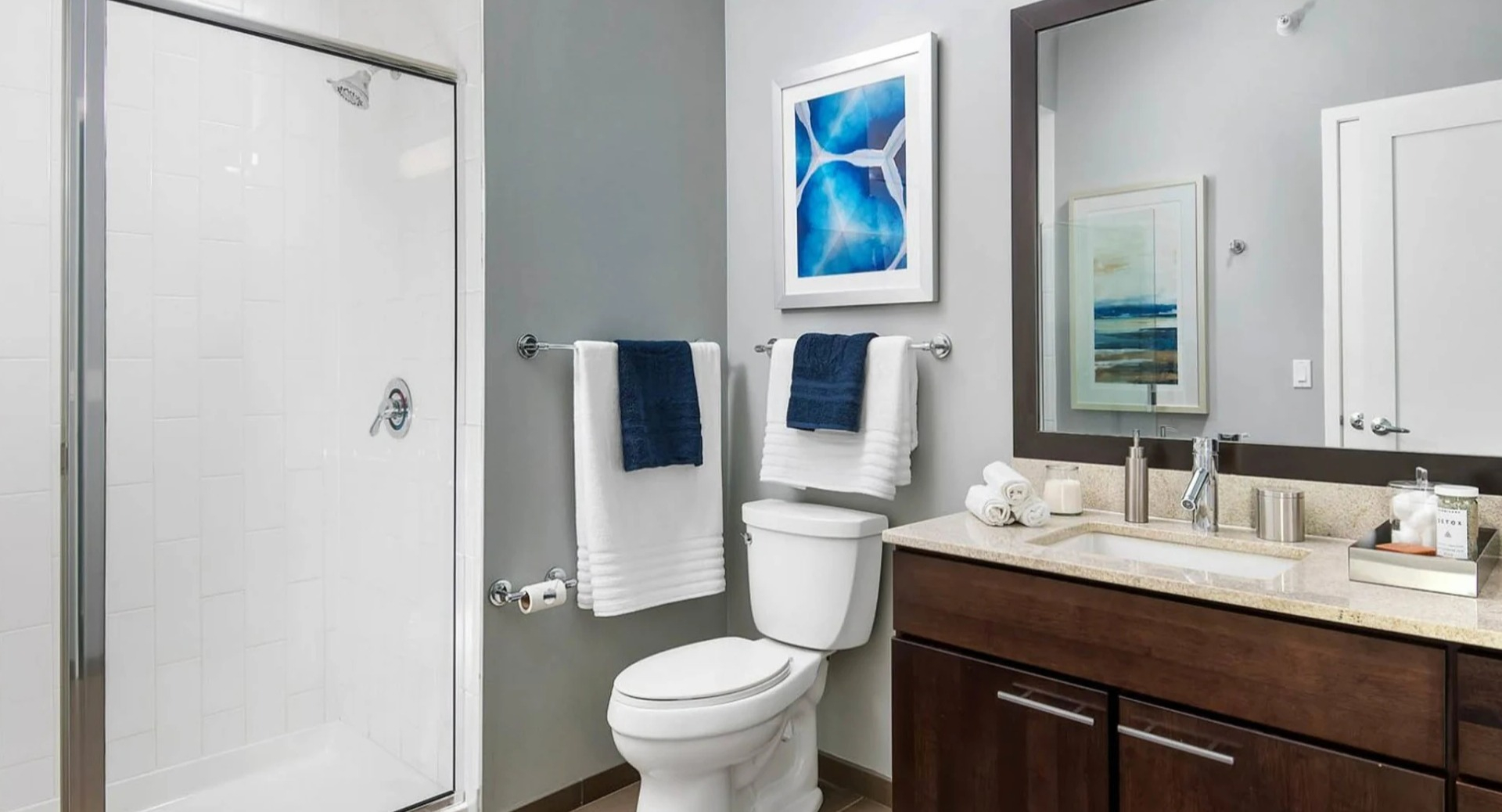Modern apartment bathroom at Parc Huron in Chicago, featuring a walk-in shower, vanity with storage, and contemporary fixtures
