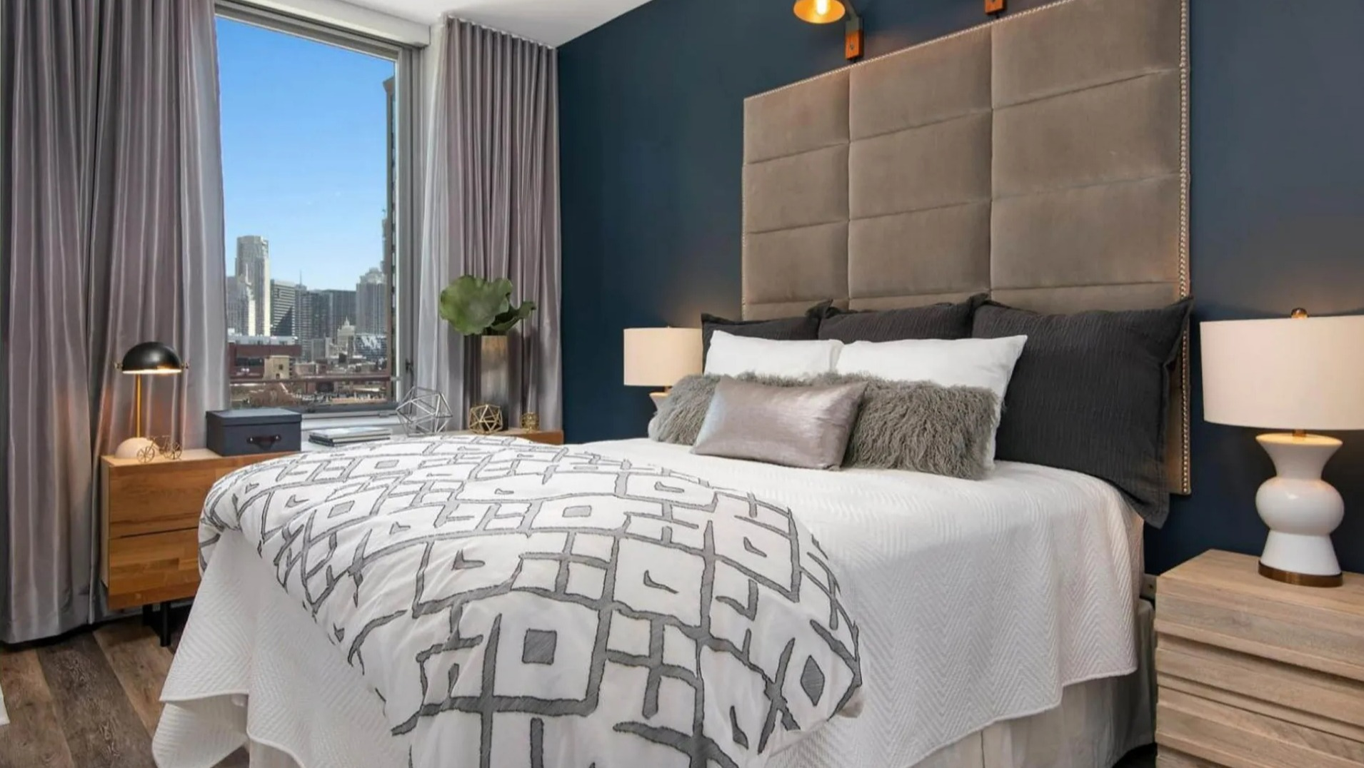 Stylish bedroom at Parc Huron in Chicago, featuring a large bed, modern decor, and expansive city views through floor-to-ceiling windows