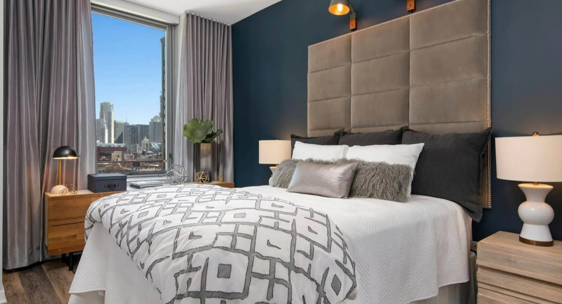Stylish bedroom at Parc Huron in Chicago, featuring a large bed, modern decor, and expansive city views through floor-to-ceiling windows