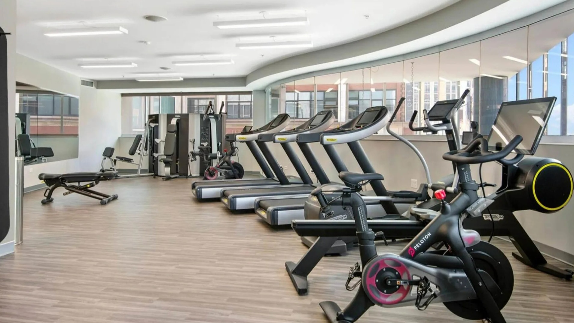 Well-equipped fitness center at Parc Huron in Chicago, featuring various cardio machines, including Pelotons, and ample workout space