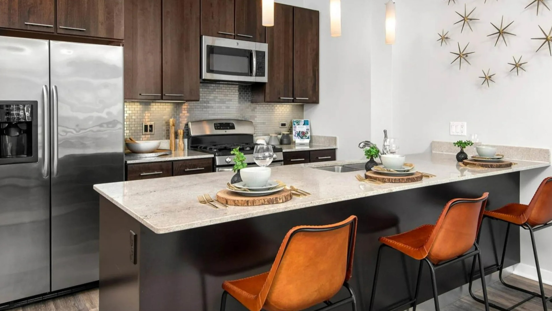 Contemporary apartment kitchen at Parc Huron in Chicago, featuring a spacious island with bar seating, stainless steel appliances, and dark cabinetry