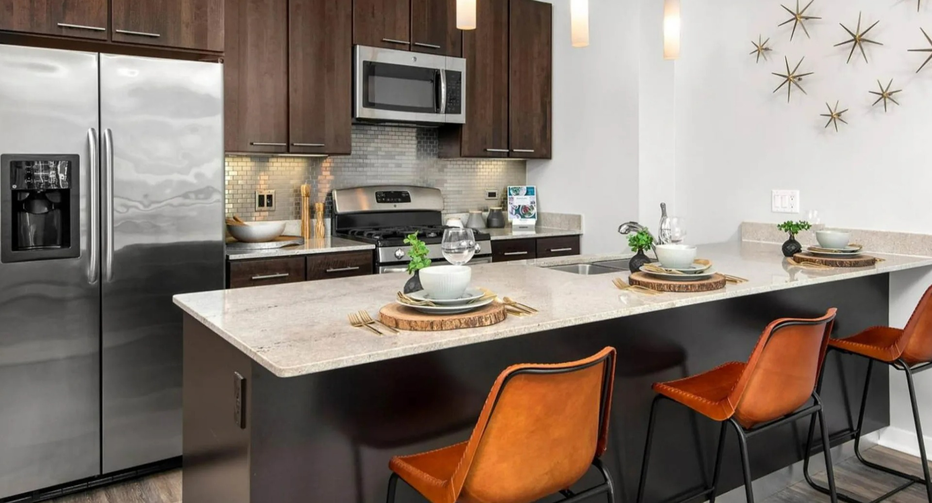 Contemporary apartment kitchen at Parc Huron in Chicago, featuring a spacious island with bar seating, stainless steel appliances, and dark cabinetry