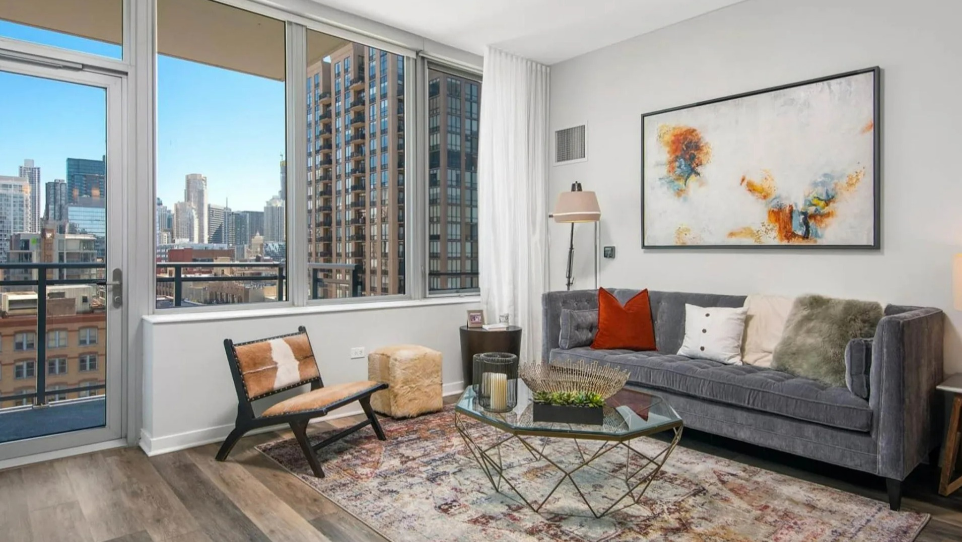 Inviting living room at Parc Huron in Chicago, featuring a comfortable sofa, modern art, and access to a balcony with city views