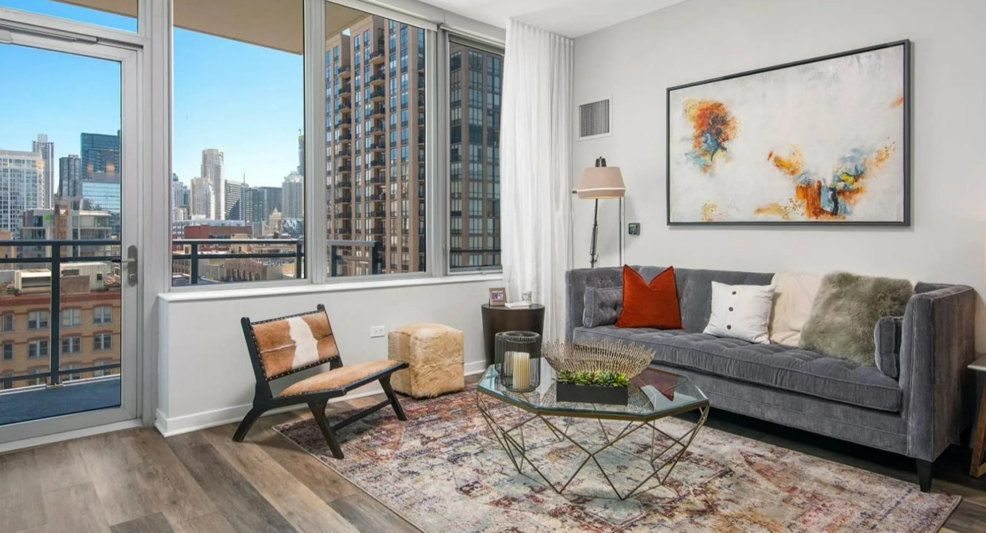 Inviting living room at Parc Huron in Chicago, featuring a comfortable sofa, modern art, and access to a balcony with city views
