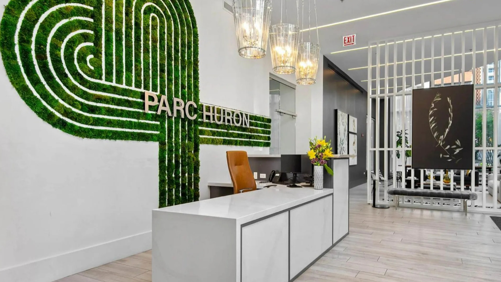 Vibrant lobby reception at Parc Huron in Chicago, featuring a modern desk, a unique moss green wall art, and elegant lighting