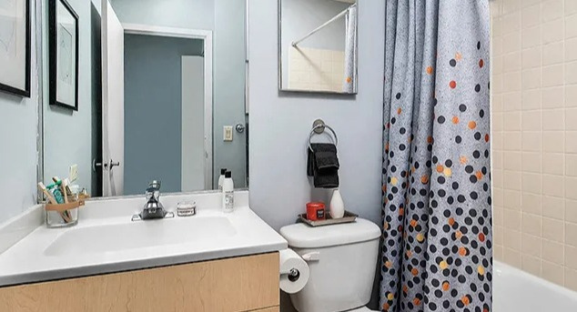 Classic bathroom with a vanity, mirror, and a bathtub with a polka-dot shower curtain at Park Michigan in Chicago