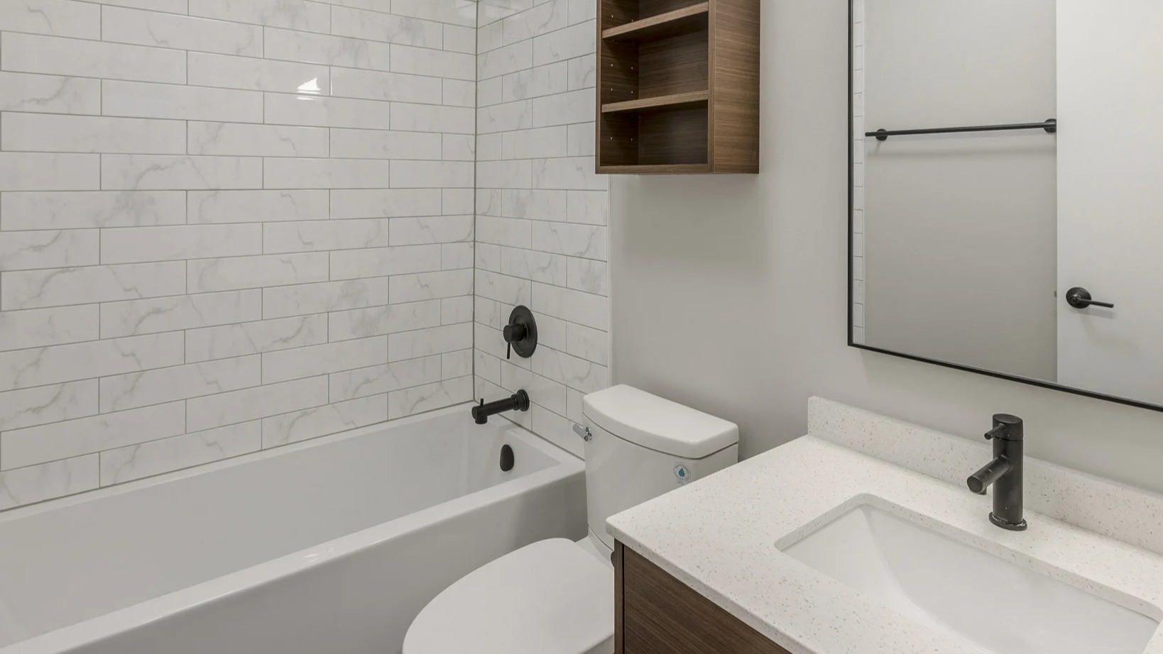 Clean bathroom with white subway tiled walls, a bathtub, and a modern vanity with wood shelving at Park Michigan in Chicago