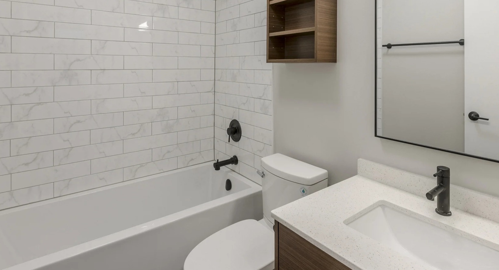 Clean bathroom with white subway tiled walls, a bathtub, and a modern vanity with wood shelving at Park Michigan in Chicago