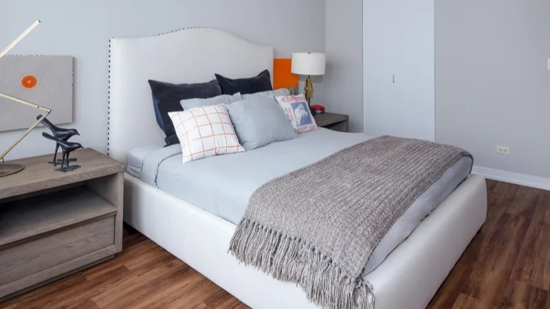 Cozy bedroom with a white upholstered bed, modern nightstands, and dark gray accents at Park Michigan apartments in Chicago