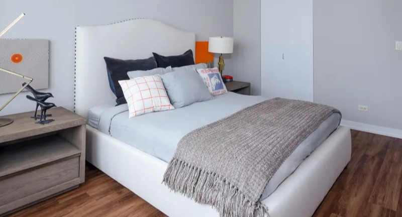 Cozy bedroom with a white upholstered bed, modern nightstands, and dark gray accents at Park Michigan apartments in Chicago