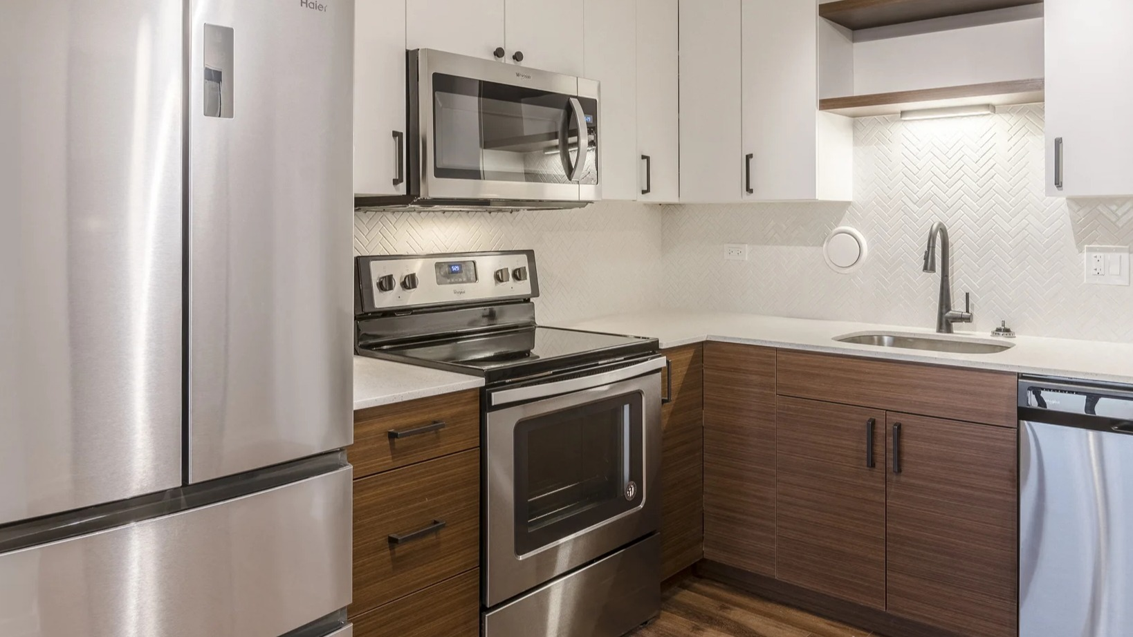 Modern kitchen with white and wood cabinetry, stainless steel appliances, and a stylish backsplash at Park Michigan in Chicago