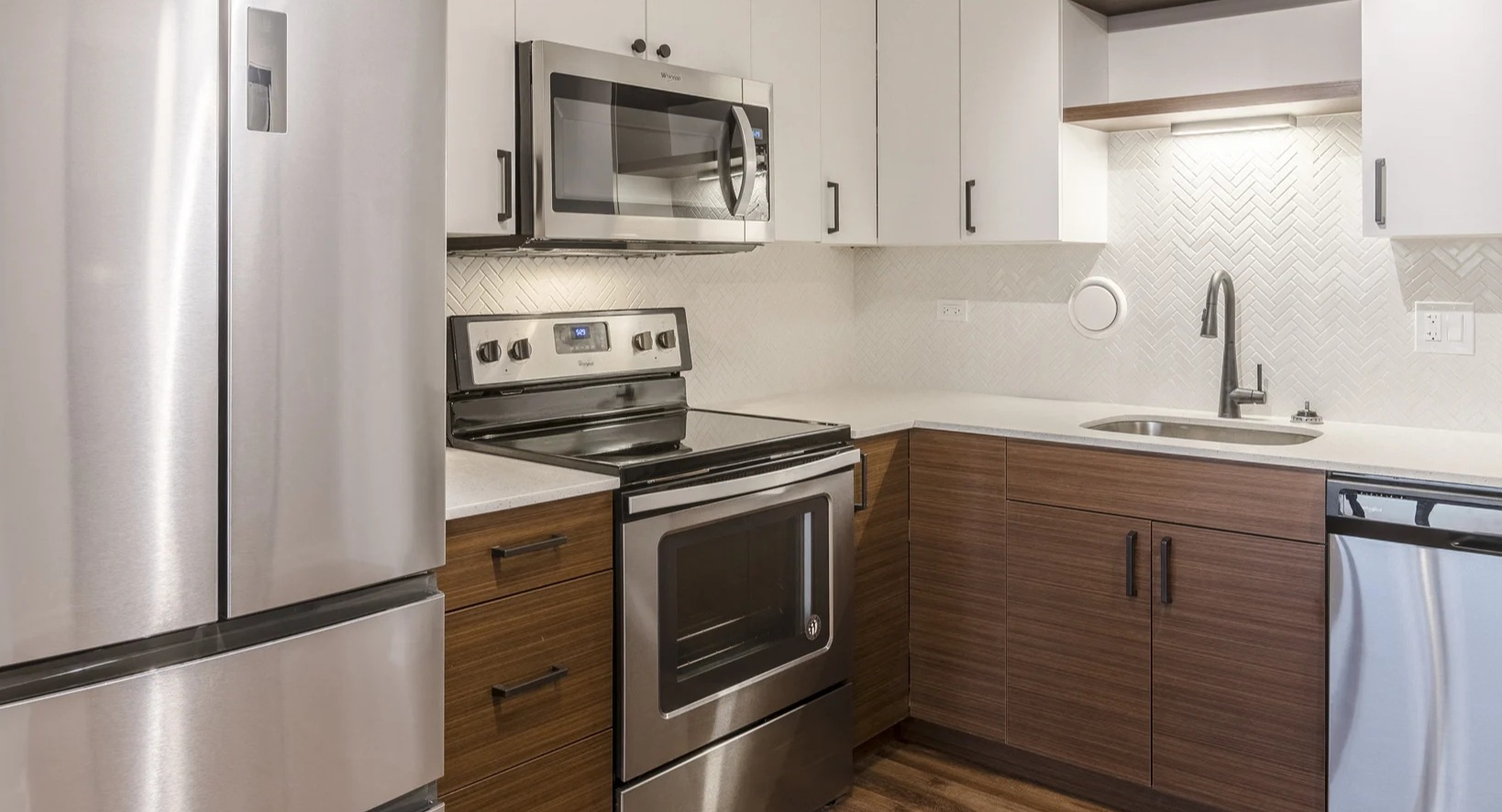 Modern kitchen with white and wood cabinetry, stainless steel appliances, and a stylish backsplash at Park Michigan in Chicago