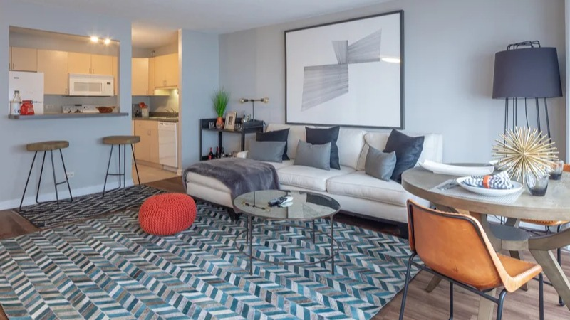 Spacious open-concept living and dining area with a sectional sofa, dining table, and a colorful rug at Park Michigan in Chicago