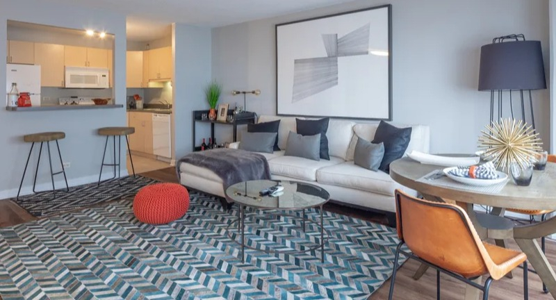 Spacious open-concept living and dining area with a sectional sofa, dining table, and a colorful rug at Park Michigan in Chicago