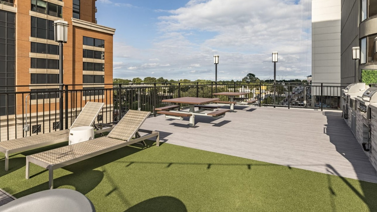 Rooftop amenity deck with lounge chairs, picnic tables, and grilling stations, surrounded by city views at Park Michigan in Chicago