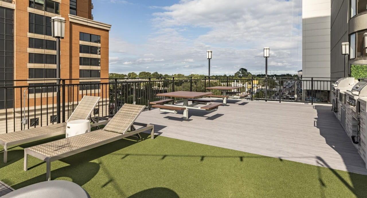 Rooftop amenity deck with lounge chairs, picnic tables, and grilling stations, surrounded by city views at Park Michigan in Chicago